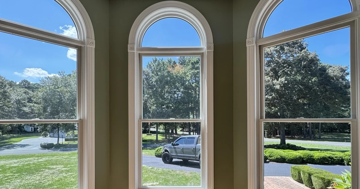 Arched residential windows overlooking trees and a lawn in Laurel